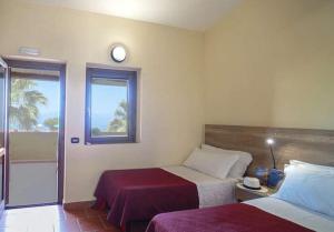 a bedroom with two beds and a clock on the wall at Torre Sant'Irene Club in Sant'Irene-Briatico