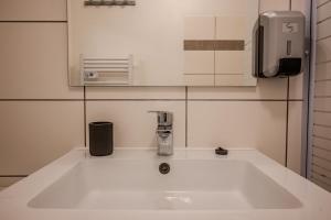 a white sink in a bathroom with a phone at Ma Préférence - Studio Cozy - Parking Gratuit - Proche Commerces & Transports in Horbourg +29 photos