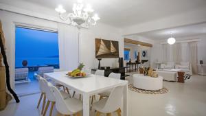 a dining room and living room with a white table and chairs at Maison Haute Mykonos in Ornos
