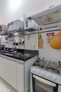 a white kitchen with a stove and a sink at Quartos privativos - São Domingos, Niterói in Niterói