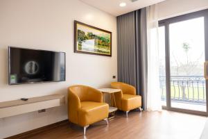 a living room with two chairs and a tv at Mai Lakeside Hotel Ninh Binh in Kỳ Vĩ +11 photos
