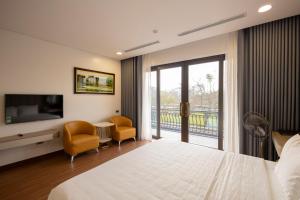 a bedroom with a bed and a tv and a balcony at Mai Lakeside Hotel Ninh Binh in Kỳ Vĩ