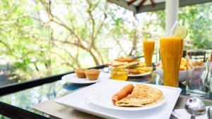 a table with plates of breakfast foods and orange juice at Green leaf Villa in Dambulla