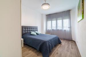 a bedroom with a bed with a blue blanket and a window at El Nido in Gavà