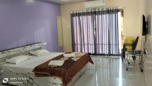 a bedroom with a bed and a large window at Saisha Palace Hotel, Ganpatipule in Ganpatipule