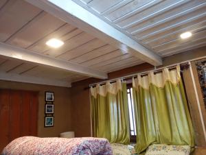a room with green curtains and a ceiling at Sunset Homestay in Sainj +11 photos