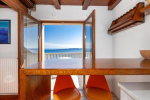 a dining table with orange chairs and a view of the ocean at Brela Seaview Apartment with Swimming Pool & Parking in Brela