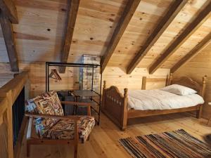 a bedroom with a bed and a chair in a room with wooden walls at Riverland Cottage 2 in Kolašin
