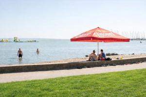 a group of people sitting under an umbrella on a beach at Vadkacsa Panzio in Balatonkenese