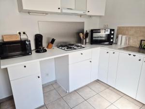 a kitchen with white cabinets and a microwave and a stove at Le lumineux-T2 calme-animaux acceptés-place auto in Saint-Gaudens