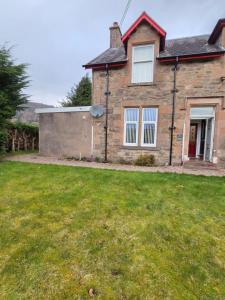 a brick house with a grass yard in front of it at Ardgay in Fort Augustus