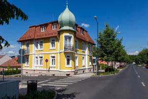 a yellow building with a green turret on a street at Villa Lucia in Hévíz