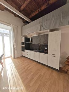 a large kitchen with white cabinets and a wooden floor at La Dimora di Tuya Superior in Naples