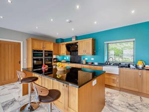 a large kitchen with blue walls and wooden cabinets at 4 Bed in Talsarnau oc-96164 in Talsarnau