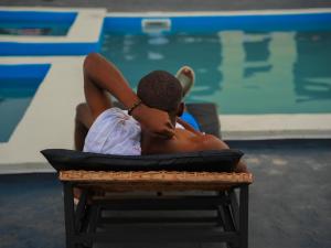 a man sitting in a chair next to a swimming pool at SKY KENAKO HOTEL in Kribi