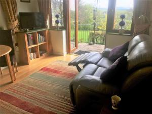 a living room with a leather couch and a large window at 1 Bed in Lampeter oc-43288 in Tregaron +29 photos