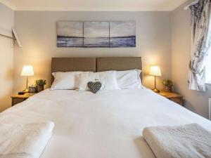 a bedroom with a large white bed with two lamps at 2 Bed in Narberth oc-tc84026 in Narberth +6 photos