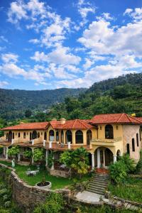 a large yellow building with a red roof at The Orchard at Peora Estates in Mukteshwar