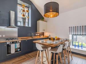 a kitchen with blue cabinets and a wooden table with stools at 2 Bed in Cardigan oc-83919 in Cilgerran