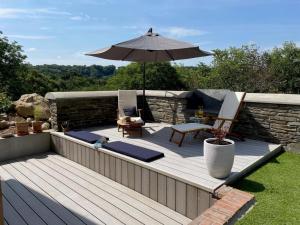 a wooden deck with an umbrella and chairs at 2 Bed in Cardigan oc-83919 in Cilgerran