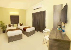 a hotel room with two beds and a television at Hotel I Live Inn in Chennai