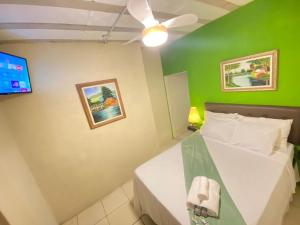 a bedroom with a white bed and a green wall at Pousada Raízes do Cipó in Serra do Cipo
