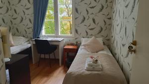 a bedroom with a bed and a desk and a window at Kartanohotelli Artturi in Söderkulla +8 photos