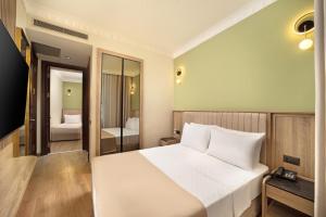 a bedroom with a large white bed and a bathroom at Atik Hotel Nişantaşı in Istanbul