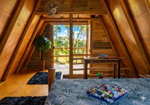 a room with a bed and a large window at Chalé Dengo Dengo - Refúgio Romântico na Serra da Mantiqueira in Pindamonhangaba