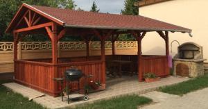 a wooden gazebo with a grill and an oven at Horváth Apartmanház in Orosháza