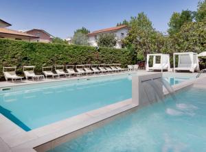 a swimming pool with chairs and a swimming pool at Hotel Capitol - Bianchi Hotels in Bellaria-Igea Marina