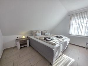a white bedroom with a bed and a table at Ferienwohnung Südwind Norddeich in Norden