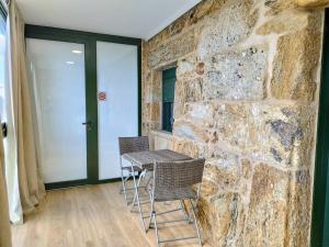 a table and chairs in a room with a stone wall at Alojamiento piñeiro arans in Oroso +3 photos
