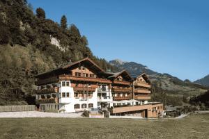 a large building in the mountains with a field at Hotel Kristall in Grossarl