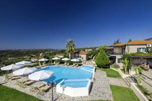 a pool with umbrellas and chairs and a house at Kefalonian Oneira Villas in Mousata