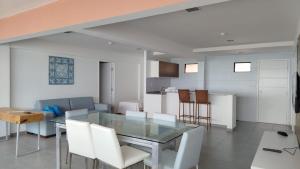 a dining room with a glass table and white chairs at Atlântico Hotel Maceió in Maceió