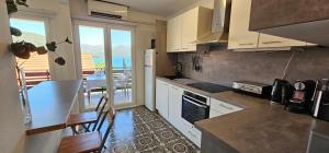 a kitchen with white cabinets and a table with chairs at Apartment MiriMore in Hodilje
