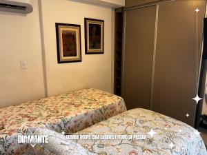 a bedroom with two beds and two pictures on the wall at Studio Diamante no CENTRO com piscina, academia e opção de vaga privativa in Juiz de Fora