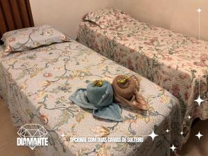 a pair of beds with a hat on top of it at Studio Diamante no CENTRO com piscina, academia e opção de vaga privativa in Juiz de Fora