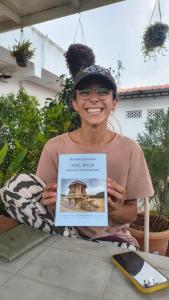 a woman holding up a picture of a building at Arasu Homestay in Antarasante