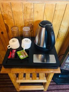 a tray with a coffee pot and glasses on a table at Mountain Nest Stay in Jibhi