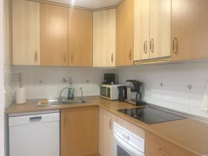 a kitchen with wooden cabinets and a sink and a microwave at Precioso duplex en Torrevieja in Torrevieja