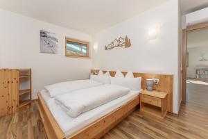 a bedroom with a bed with white sheets at Austrian Alpine Apartments in Ramsau am Dachstein