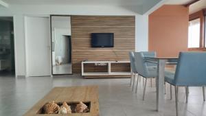 a living room with a table and chairs and a television at Atlântico Hotel Maceió in Maceió