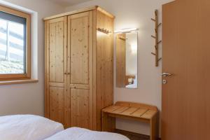 a bedroom with a wooden cabinet and a bed and a window at Austrian Alpine Apartments in Ramsau am Dachstein +77 photos