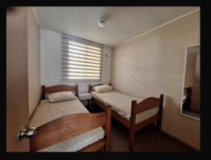 a small room with two beds and a window at Departamento COPAYAPU in El Cerrillo