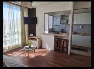 a kitchen with white cabinets and a table and stool at Departamento COPAYAPU in El Cerrillo