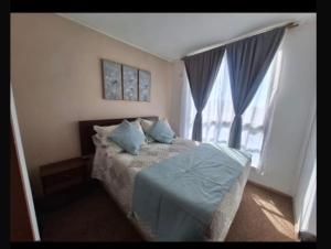 a bedroom with a bed with blue pillows and a window at Departamento COPAYAPU in El Cerrillo
