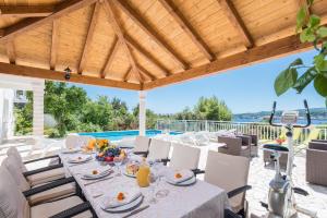 a dining table and chairs on a patio with a pool at Holiday Villa Perna in Orebić