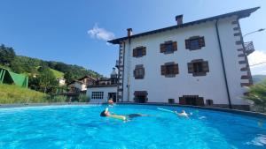a group of people swimming in a swimming pool in front of a house at Casa Rural Betraunea in Sumbilla